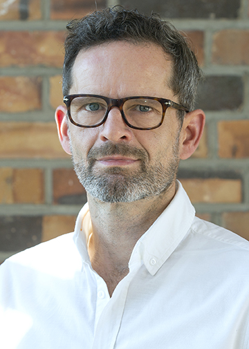 Portrait of Prof. Dr Ralf Uptmoor in front of a stone wall