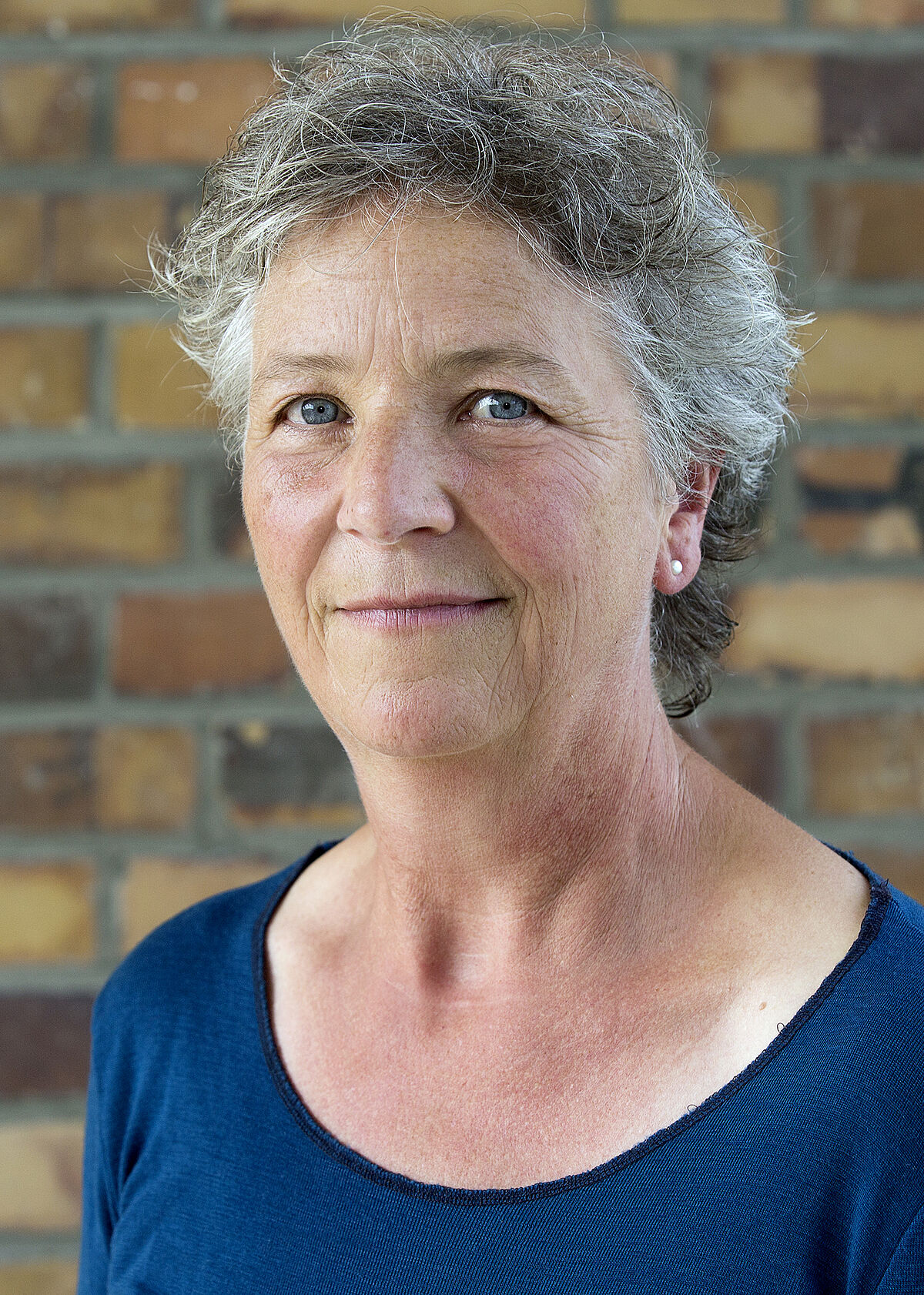 Portrait Brigitte Claus in front of a stone wall